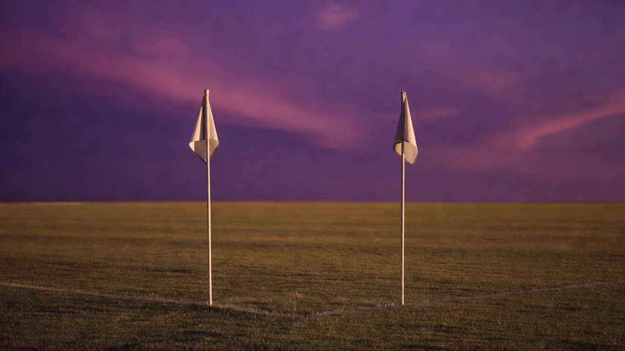 Two plain corner flags against a dramatic purple dusk sky