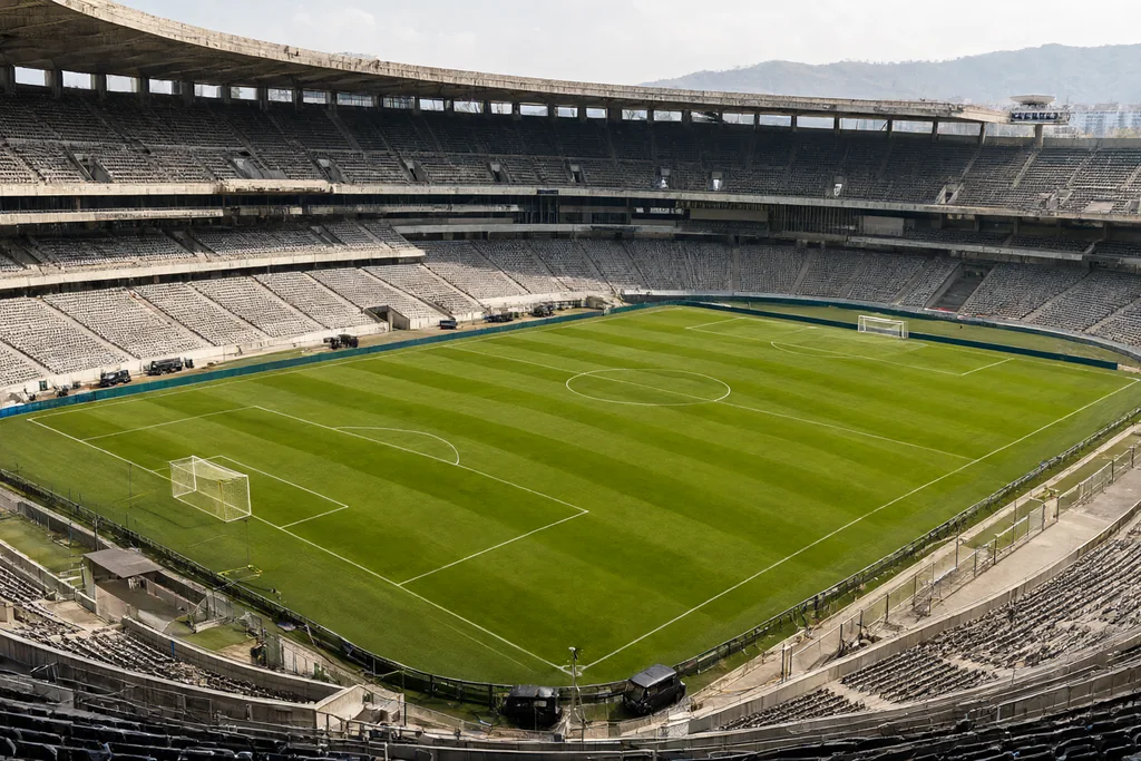 A grand old soccer stadium with steep tiered concrete stands above a bright green pitch